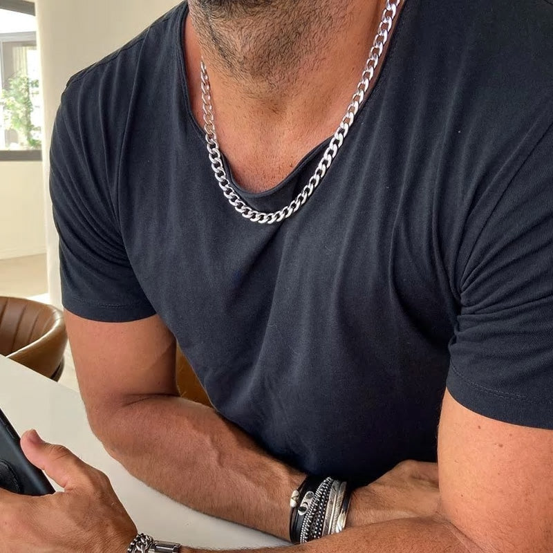 A man wearing a black shirt and a stainless steel curb chain necklace.